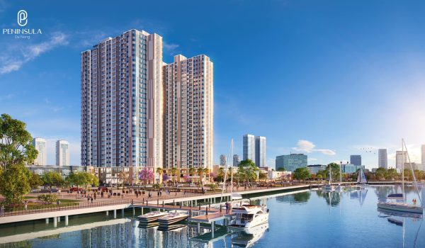 Modern residential building complex with multiple high-rise towers near a marina, featuring boats and landscaped areas.